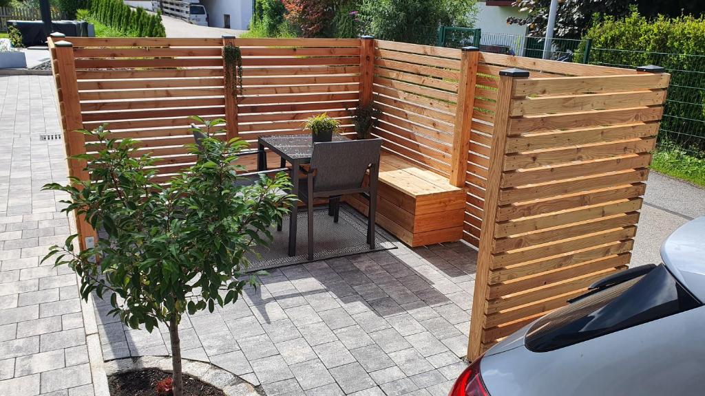 a wooden privacy fence with a table and a tree at Ferienwohnung Ehring in Kiefersfelden