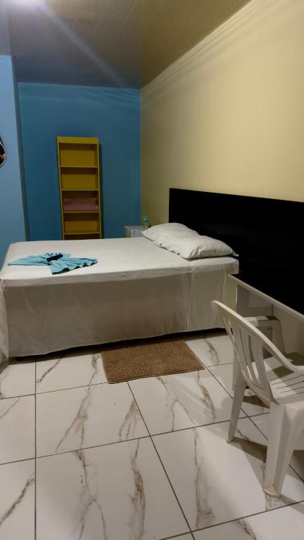 a bedroom with a bed and a white chair at Hotel e Residencial Solar in Uruara