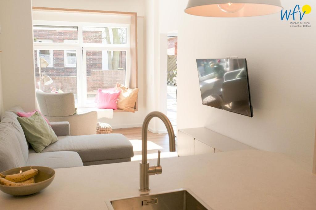 a living room with a couch and a tv on the wall at Stine's Hus Ferienwohnung 2 in Borkum