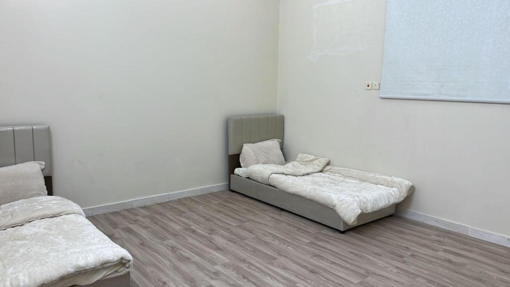a room with two beds and a white wall at شقه مفروشه in Hail