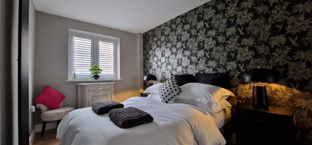 a bedroom with two beds with white sheets and floral wallpaper at Kings Sconce in South Muskham