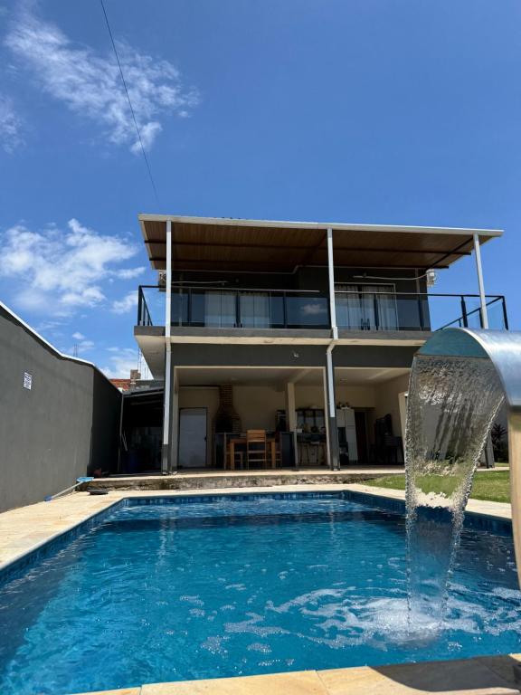 a swimming pool with a fountain in front of a house at Chácara Vittorino in Artur Nogueira