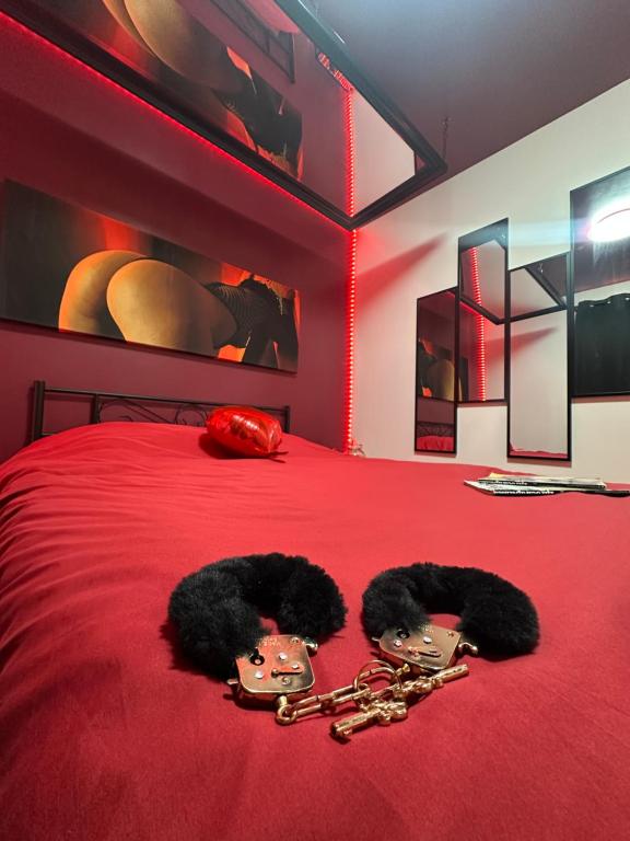 a bedroom with a red bed with two chains on it at 145 désirs in Samer