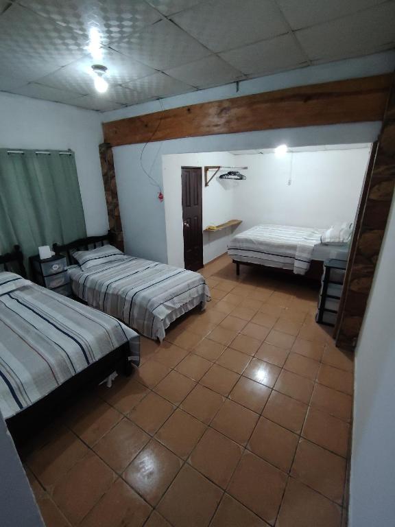 a bedroom with two beds and a tiled floor at Casa Amarilla hostel in Bajo Boquete