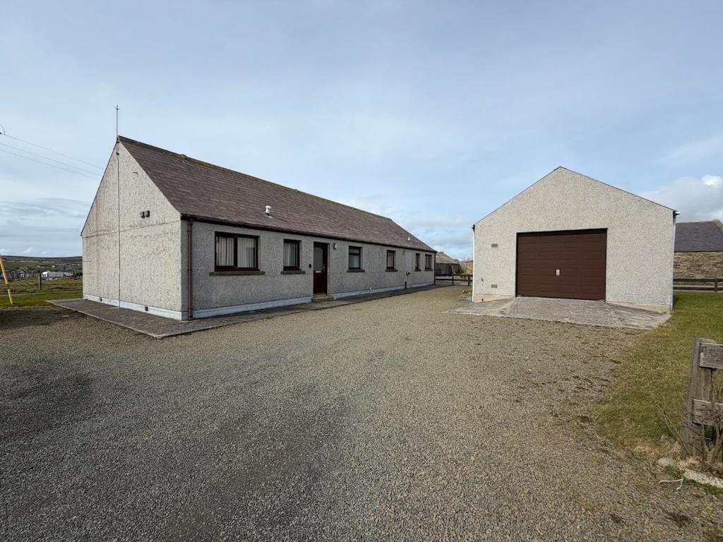 two white buildings on a dirt road in a field at Ben Alder Spacious 3 Bedroom House in Orkney