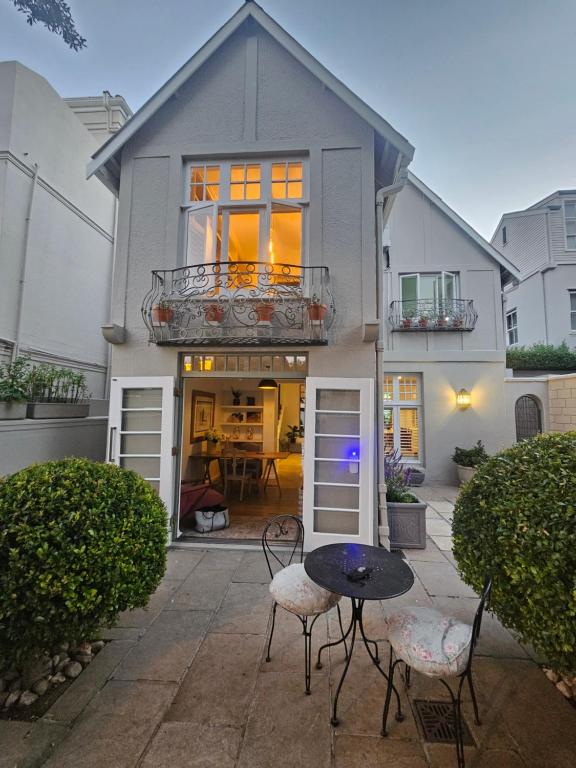a house with a table and chairs in front of it at Cherry Tree House, Newlands in Cape Town