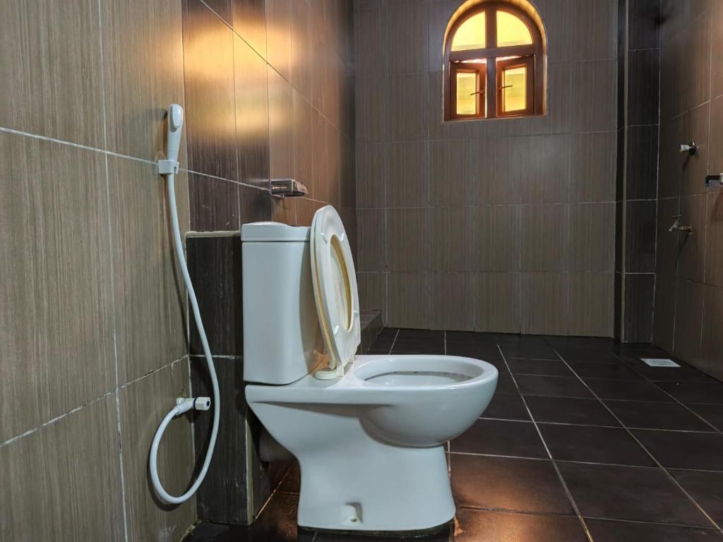 a bathroom with a toilet with a shower and a window at Ocean Breeze Nook in Mombasa