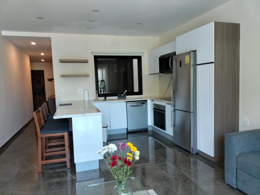a kitchen with a refrigerator and a table with a vase of flowers at Condo arrosito village in Tangolunda