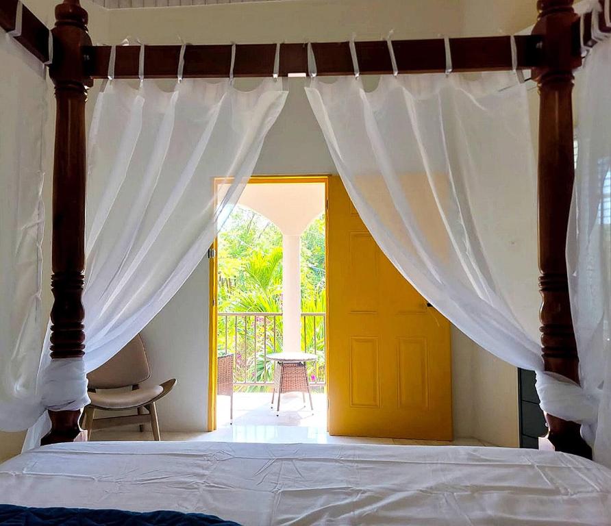 a bedroom with a canopy bed with a yellow door at Home Escape Negril Unit 3 in Negril