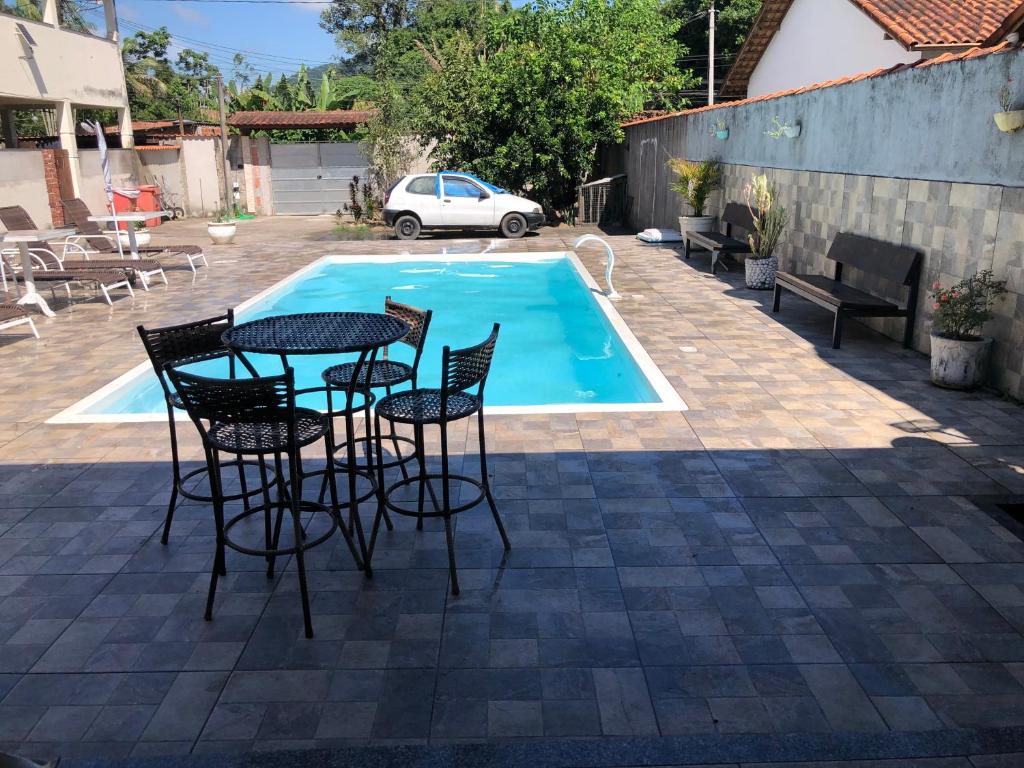 a patio with a table and chairs next to a pool at Casa da mãe joanna in Guapimirim