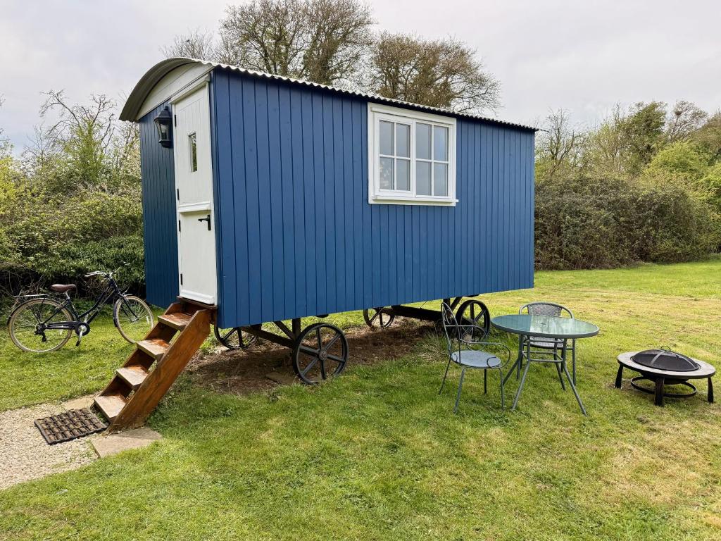 a blue tiny house with a table and chairs at Shepherd's Hut near Oxford in Cumnor