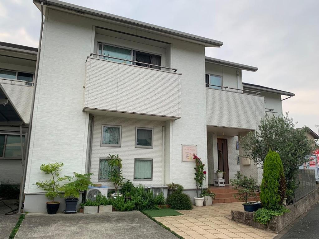 a white house with plants in front of it at ReFa room由来House in Kumamoto