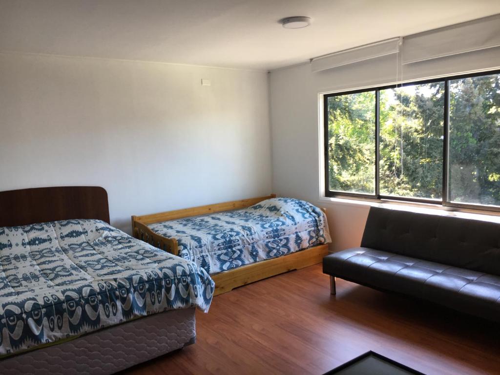 1 dormitorio con 2 camas, sofá y ventana en Departamentos y Habitaciones Centro Osorno, en Osorno