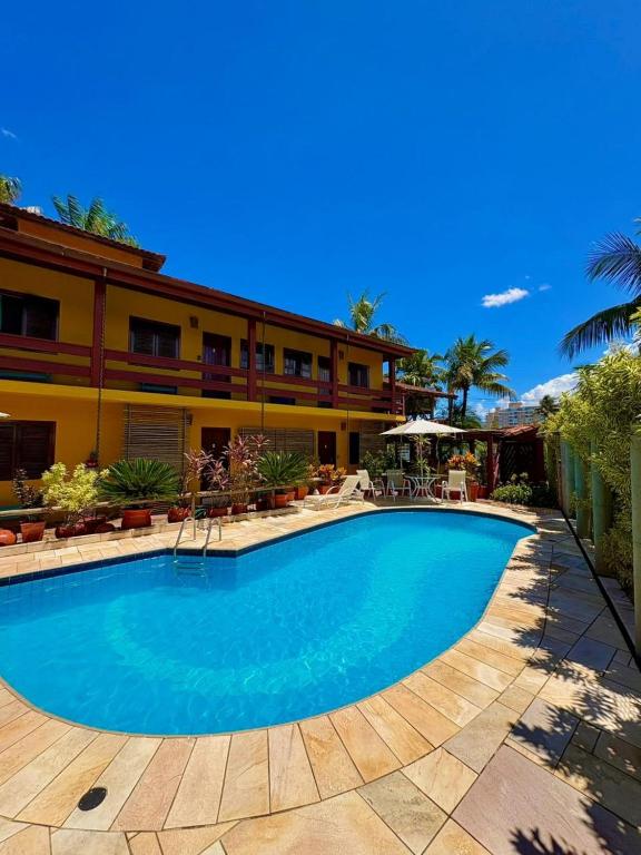 a swimming pool in front of a hotel at Residencial Villa Cris - Jd. São Lourenço/Itaguaré in Bertioga