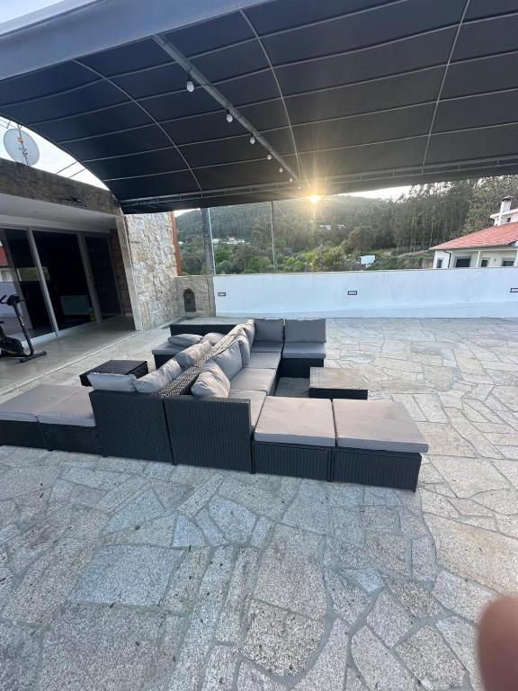 a couch sitting under a roof on a patio at Leonchic - Guest House com Piscina de Água Salgada in Barcelos