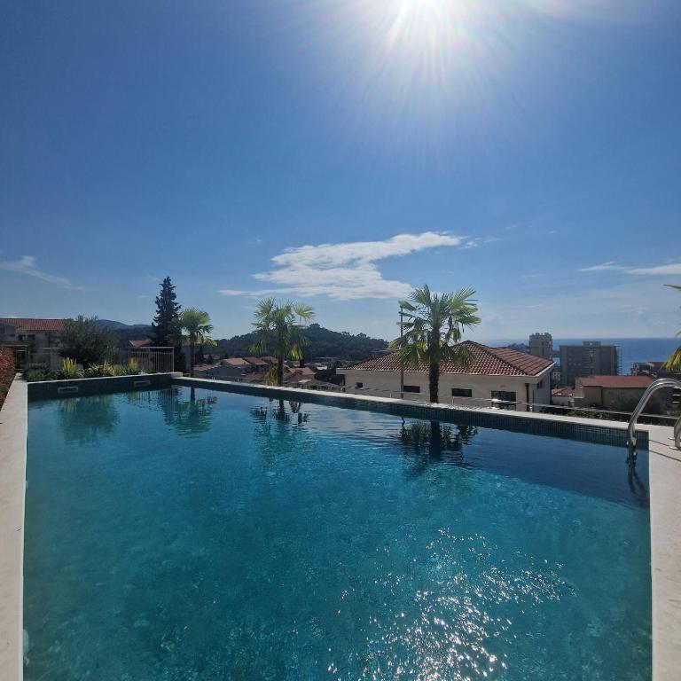 a large swimming pool with the sun in the sky at Olive residence A8 in Petrovac na Moru