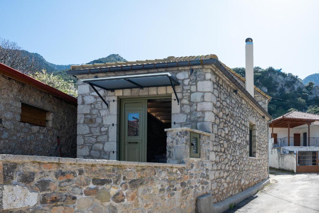 a stone building with a green door on it at Achyronas 1840 Stone House in Graviá