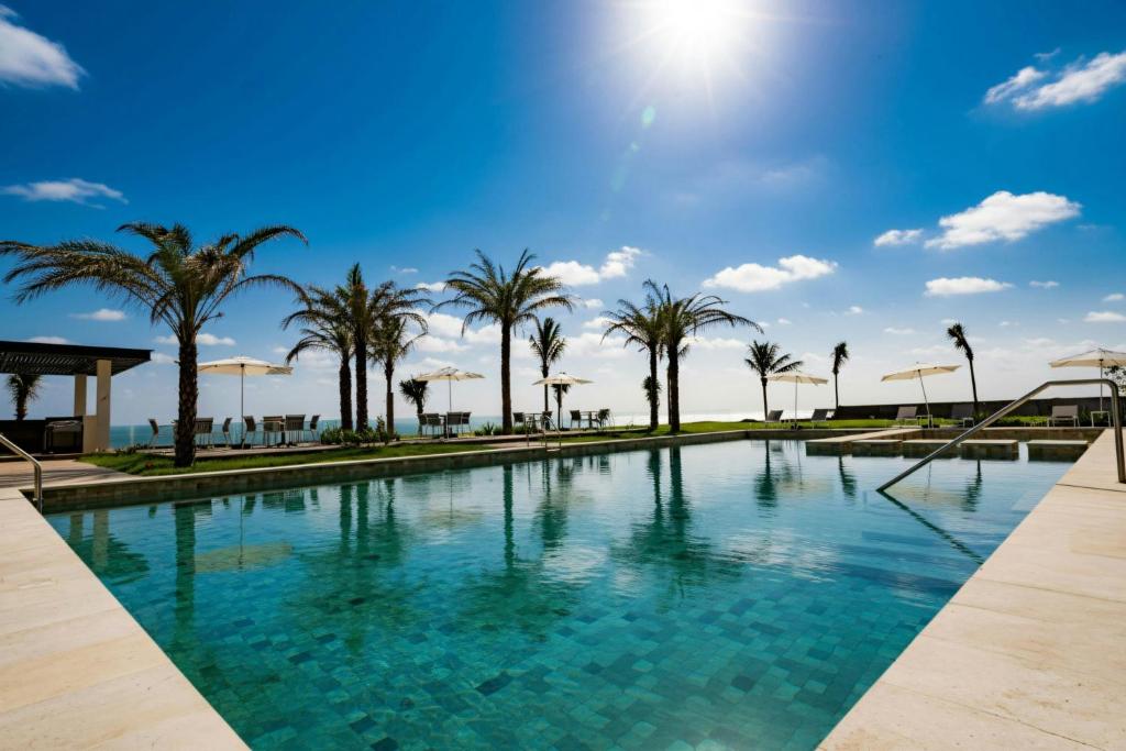 a swimming pool with palm trees and a blue sky at Delta Hotels by Marriott Riviera Veracruz in Heroica Alvarado