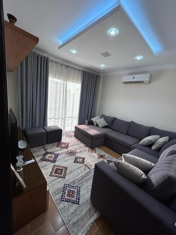 a living room with a couch and a tv at Decent brand new flat with garden view in New cairo