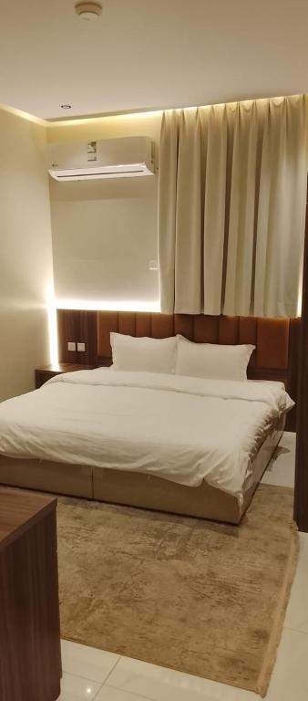 a bedroom with a large bed and a window at شقة واحة رتيل الفندقية in Al-ʿUla