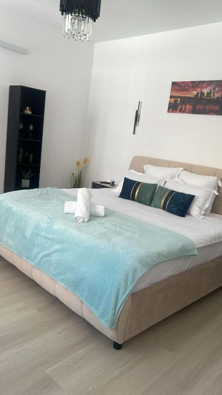 a bedroom with a large bed with a blue blanket at Uniri Urban Escape in Craiova
