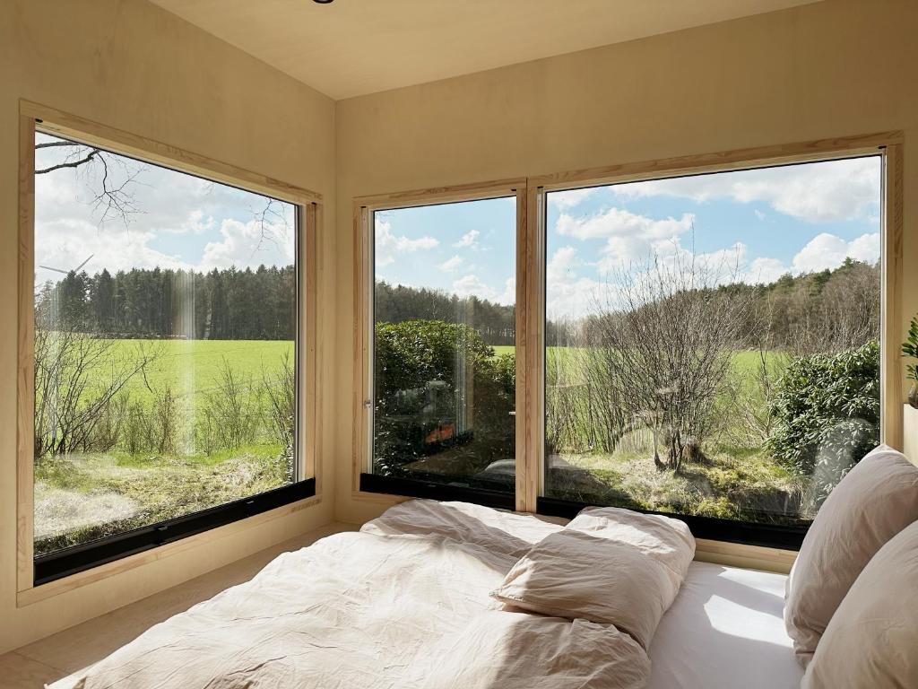 a bedroom with a bed and two large windows at Tiny House 2 mit Garten in der Lüneburger Heide in Soltau