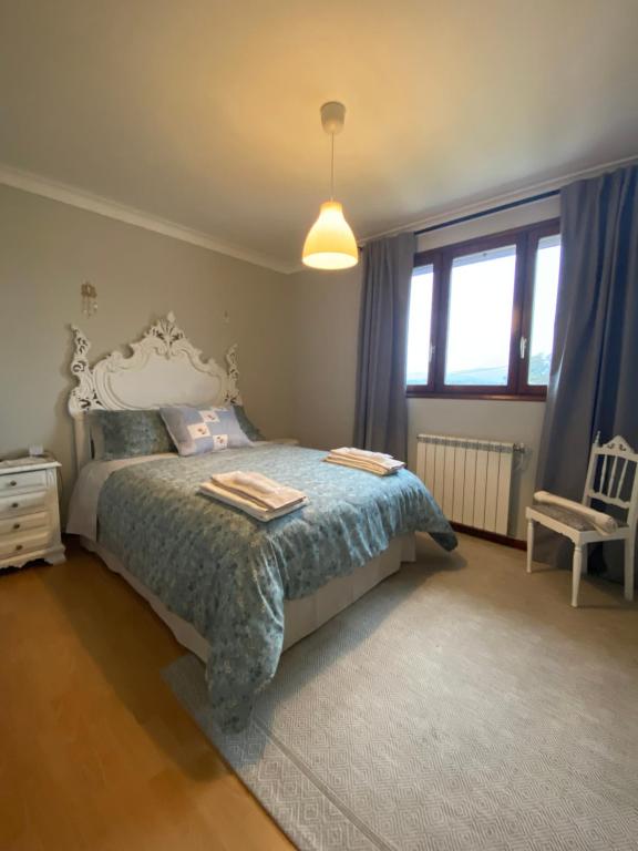 a bedroom with a bed and a chair and a window at A casa das hortênsias- caminho de Santiago in São Pedro da Torre
