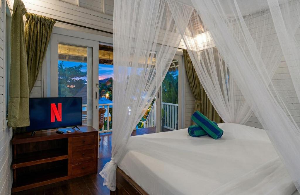 a bedroom with a bed with a tv and a window at The Dafish Ceningan in Nusa Lembongan