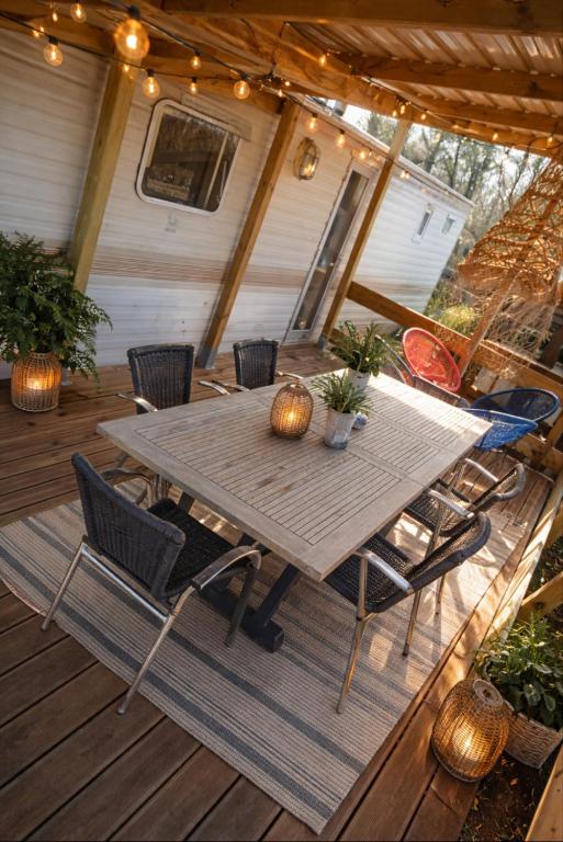 a wooden table and chairs on a deck at Mobil-home rénové tout confort, terrasse couverte, climatisation, arrivée autonome in Fourmies