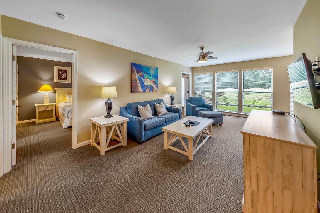 a living room with a blue couch and a bed at Golf Course Condo with Pools & Family Fun in New Bern