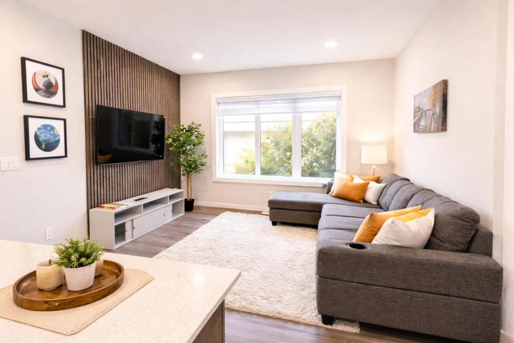 a living room with a couch and a tv at NorthEdge Suites Leduc in Leduc