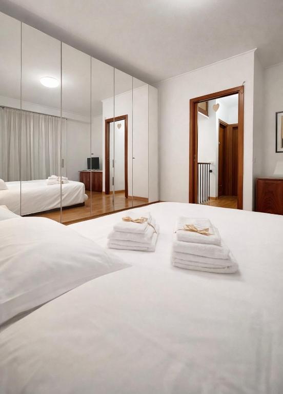 a white bedroom with two beds and a mirror at The Mazzitellis Home in Nettuno
