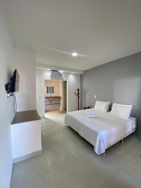 a white bedroom with a large bed and a television at 4 Ventos House in São Miguel do Gostoso