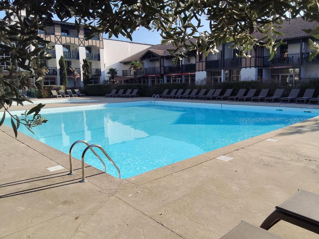 a large blue swimming pool in front of a building at Swing Moliets - T2 bis - Golf - 3 Piscines - Plage in Moliets-et-Maa