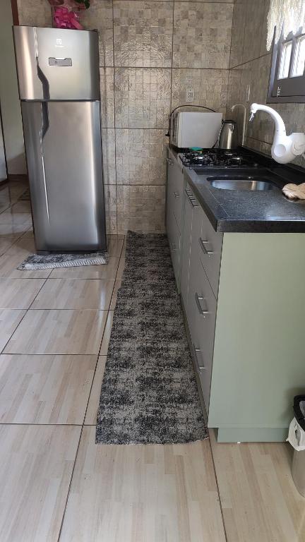 a kitchen with a refrigerator and a floor with a rug at Ospedagem leão in Praia Grande