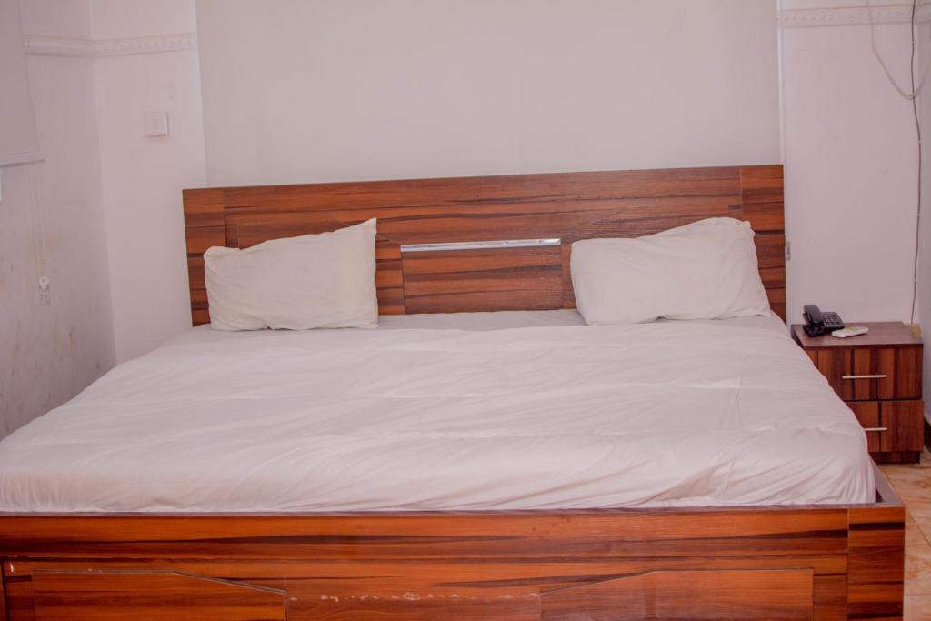 a bed with a wooden headboard and white sheets at Beulah House Lounge in Ibadan