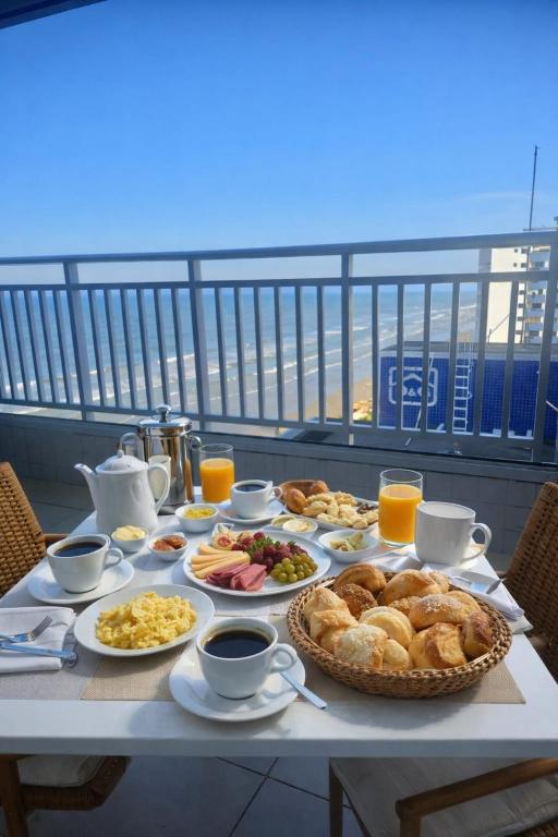 a table with breakfast foods and drinks on a balcony at Piscina Lazer Frente ao Mar in Mongaguá