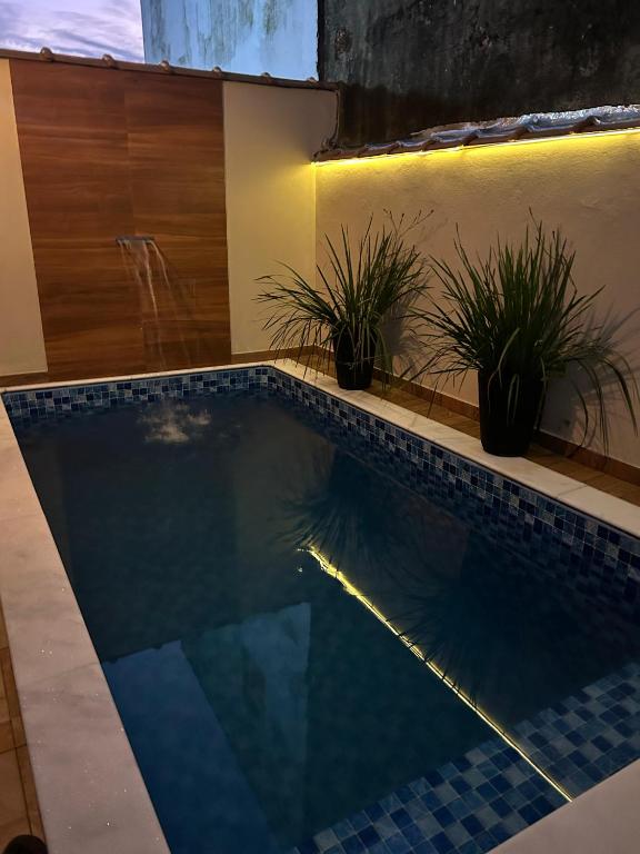 a swimming pool with potted plants in a house at Beach House 96 in Itanhaém