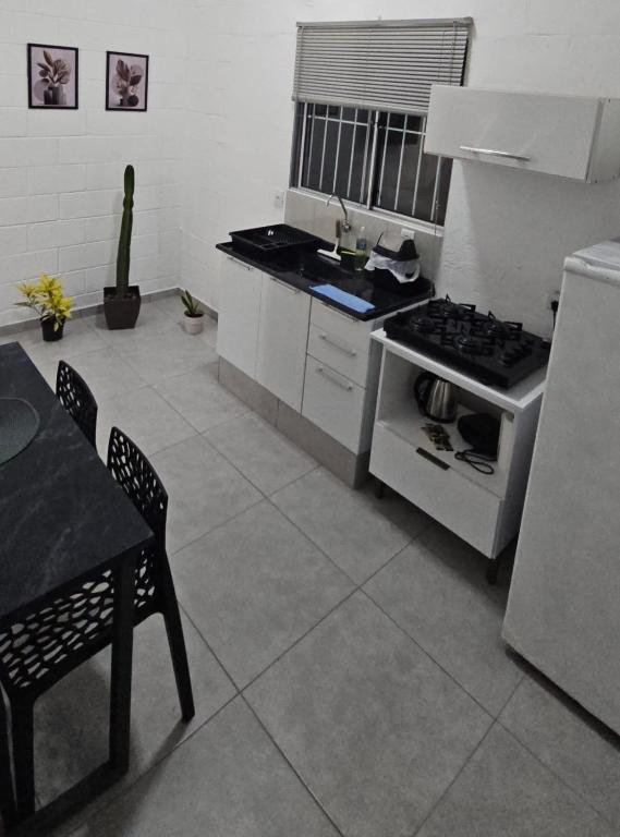 a kitchen with a stove and a table in it at Casa Completa em Cotia com estacionamento in Cotia