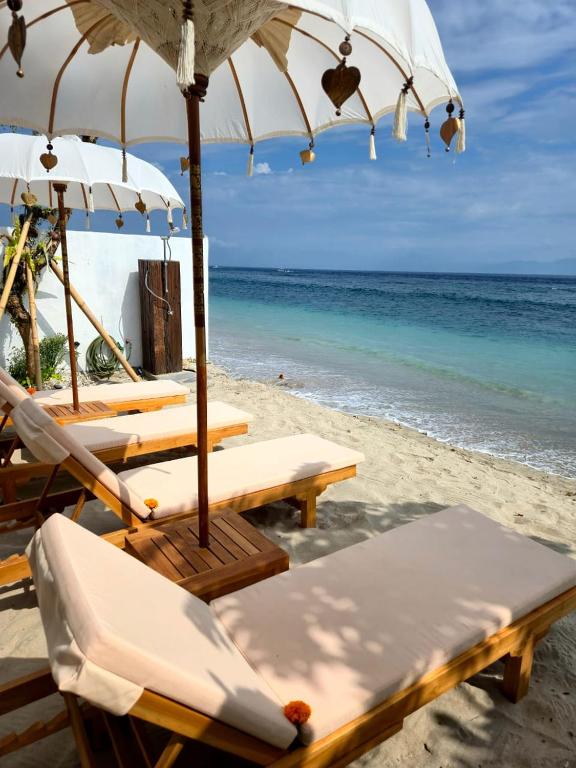a group of chairs and umbrellas on a beach at Sandy Beach Villas in Toyapakeh
