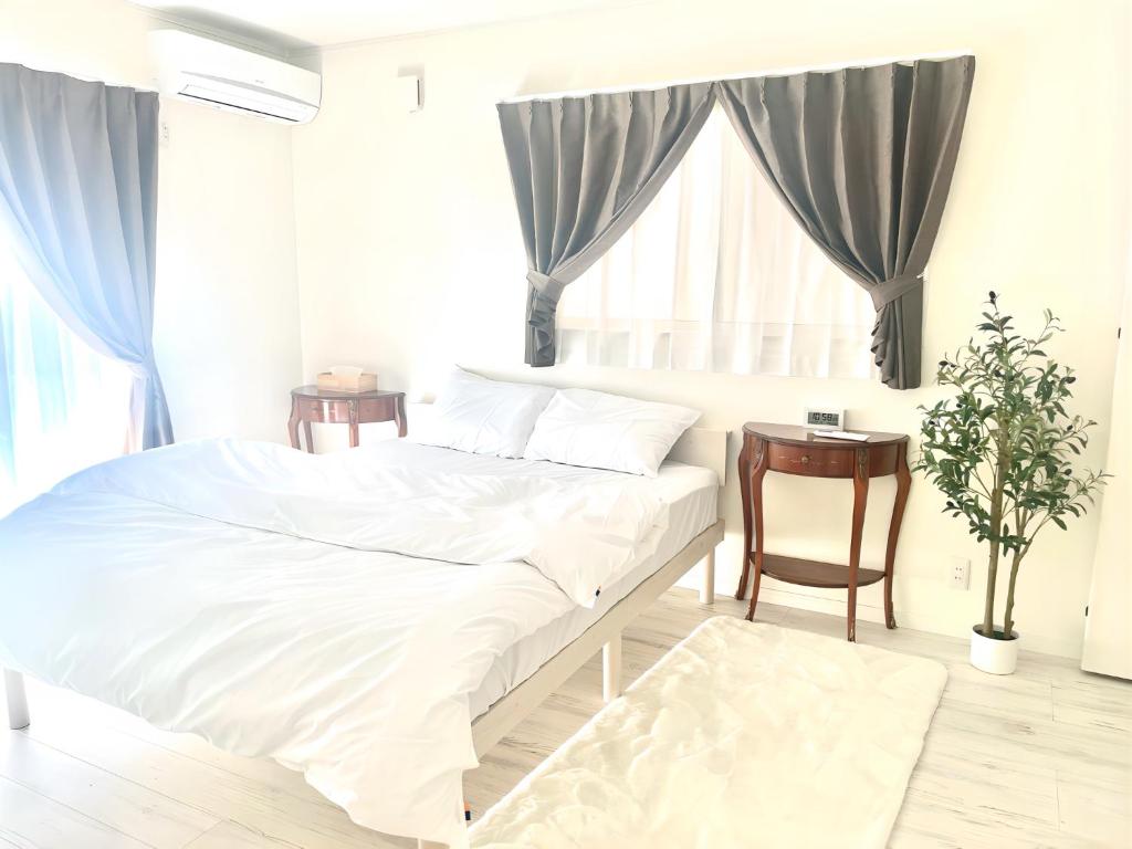 a white bedroom with a bed and a table at Sunny Inn Sumida in Tokyo