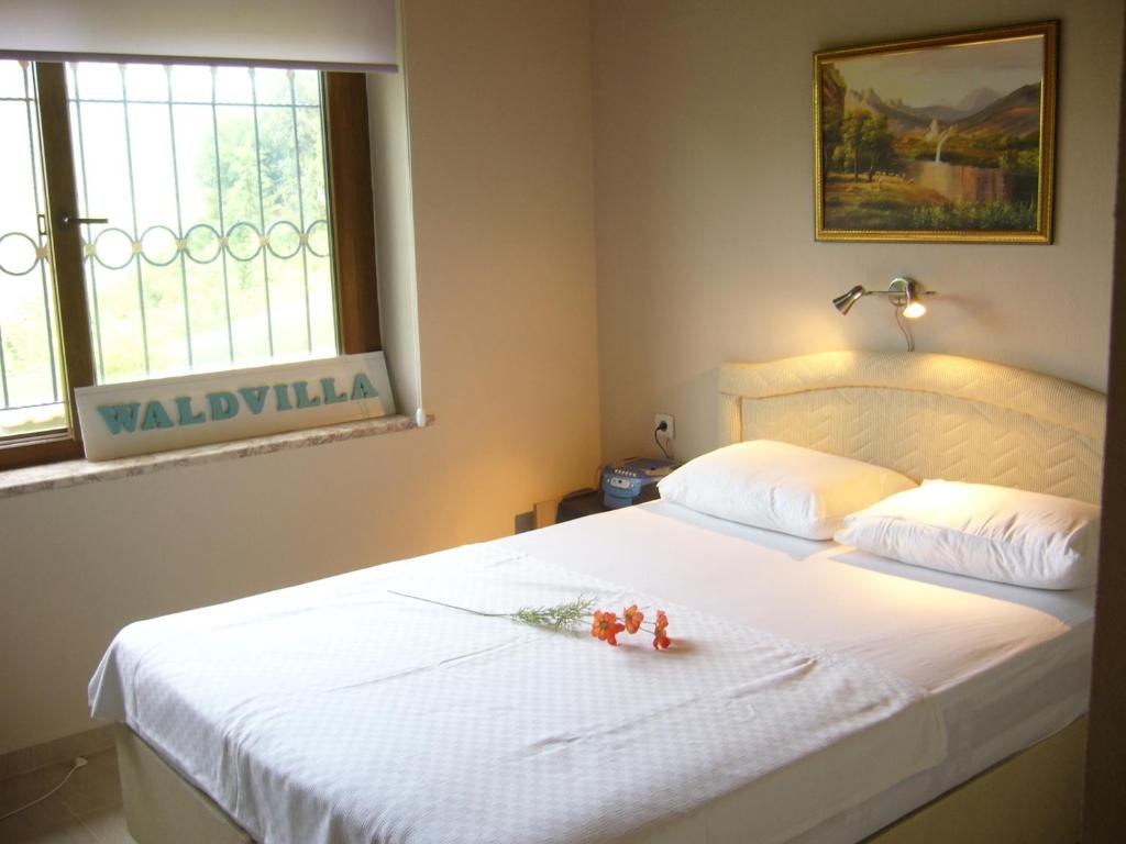 a bedroom with a white bed with flowers on it at Waldvilla in Cıralı