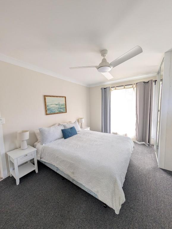 a white bedroom with a large bed and a window at Green Acres in Gympie in Monkland