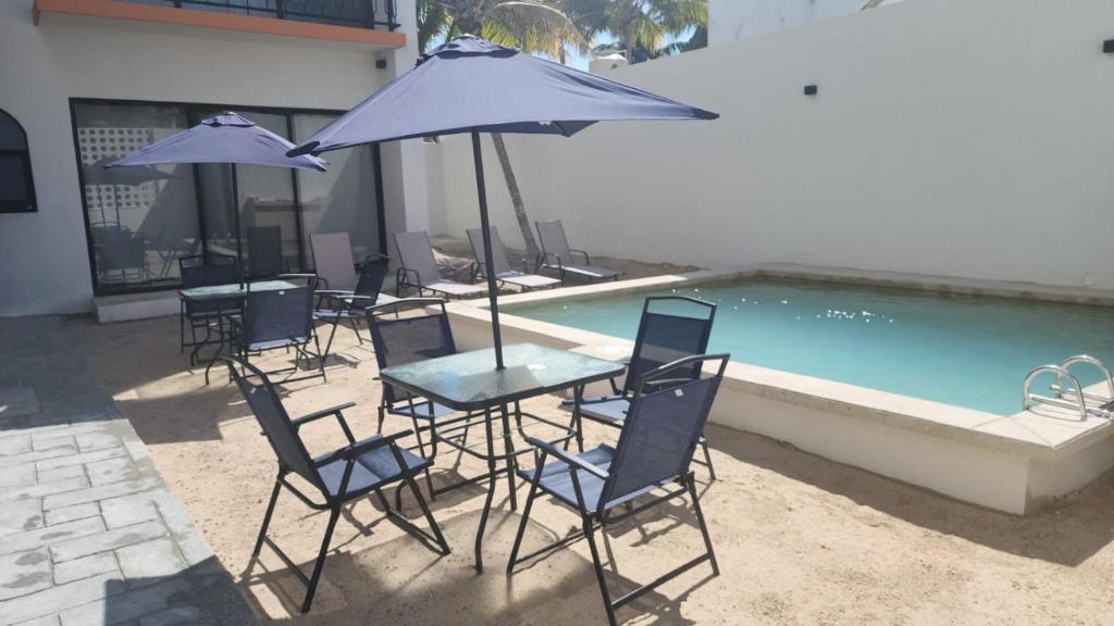 a group of chairs and tables with umbrellas next to a pool at Casa Laura Penthouse in El Cuyo