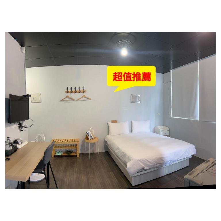 a bedroom with a bed and a desk and a tv at 好客輕旅 in Donggang