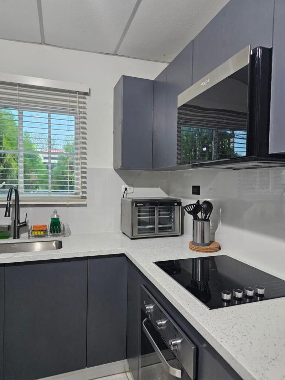 a kitchen with gray cabinets and a sink and a microwave at La Casa de Miranda in San Miguel