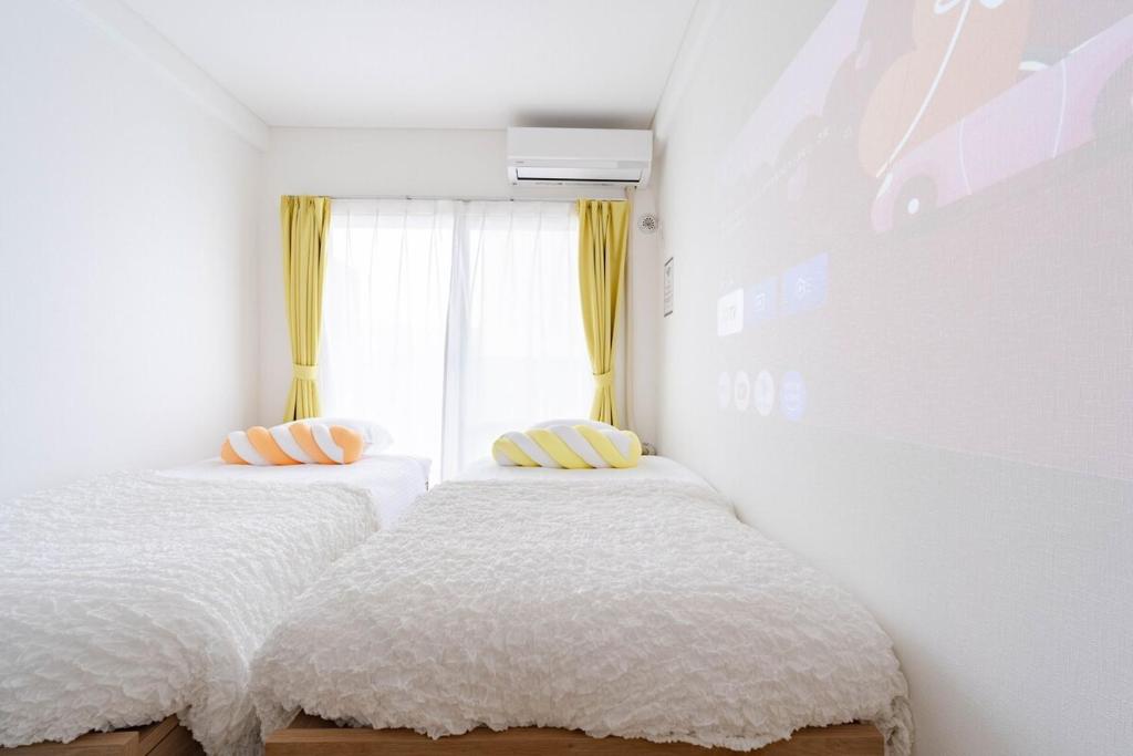 two beds in a white room with a window at アンドステイ屋形町306 in Kyoto