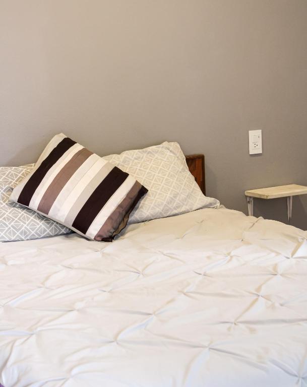 a bed with a black and white pillow on it at Real Hotel y Alojamientos in Pachuca de Soto