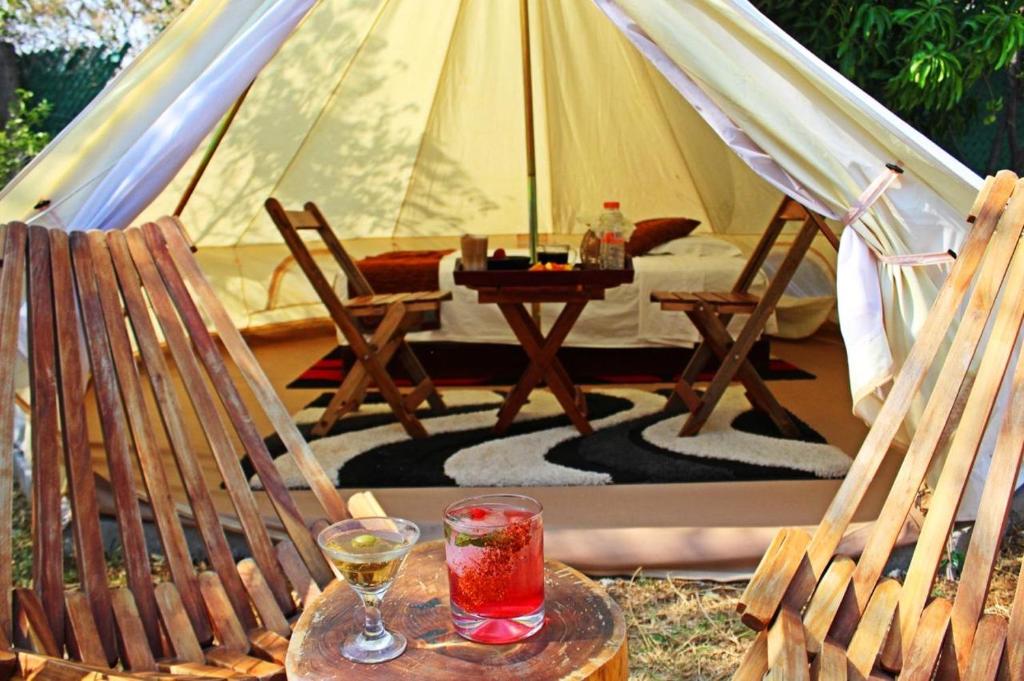 a tent with two chairs and a drink on a table at Glamping Wellness Pet Friendly El Secreto in Tepoztlán