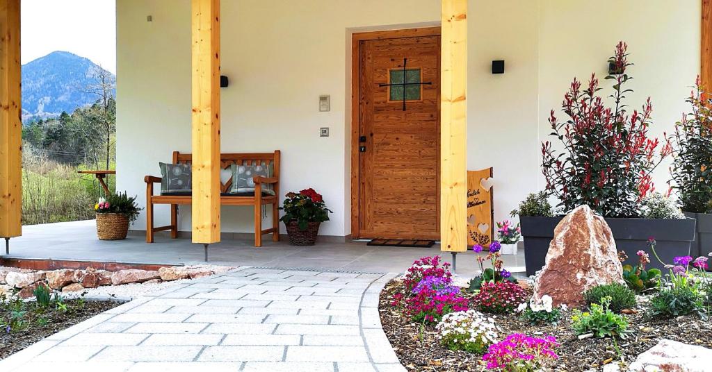 a porch of a house with a wooden door and flowers at Alpenchalet-Chiemgau in Marquartstein